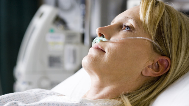 Eine Frau liegt im Krankenhausbett und wird über die Nase beatmet