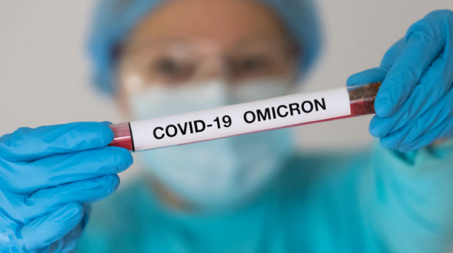 Ein Mann hält eine Testprobe mit der Aufschrift "Covid-19 Omicron" ins Bild.