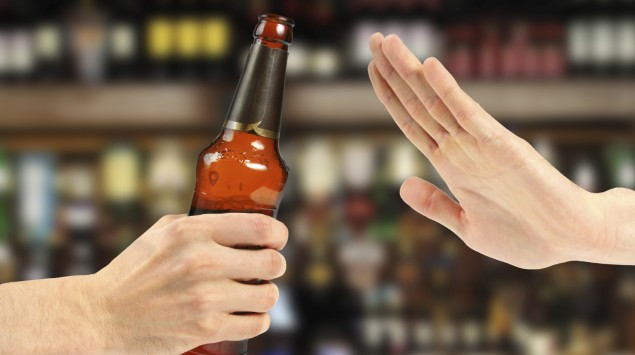 Jemand lehnt mit einer Handbewegung eine ihm angebotene Bierflasche ab.
