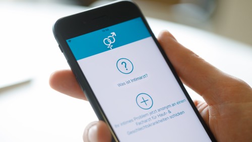 Hand hält Smartphone, auf dem die App Intimarzt geöffnet ist