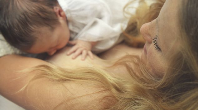 Eine junge Mutter stillt ihr Neugeborenes.
