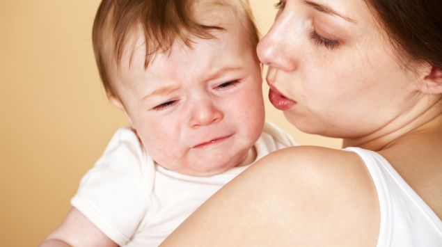Eine Frau hält ein weinendes Baby im Arm.