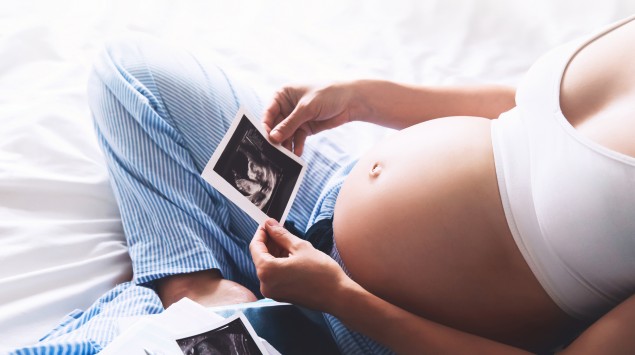 Eine Schwangere betrachtet Ultraschallbilder ihres Babys.