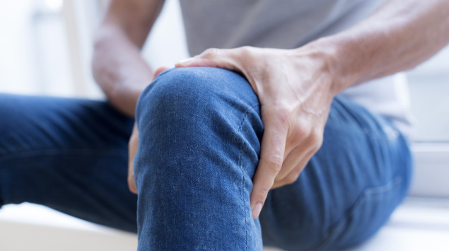 Ein Mann hält sich das Knie.