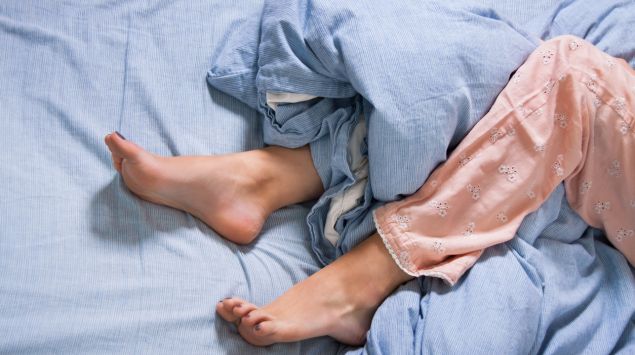 Man sieht die Beine einer Frau im Bett.
