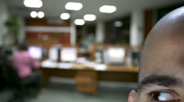 Ein Mann in einem Büro beobachtet die Szenerie im Hintergrund.