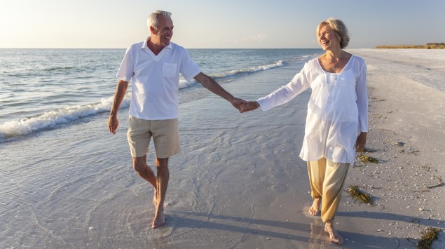 Ein älteres Paar geht am Strand spazieren.