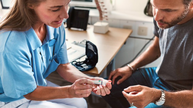Diabetes-Diagnose: Eine Ärztin erklärt einem Patienten ein Blutzuckermessgerät.