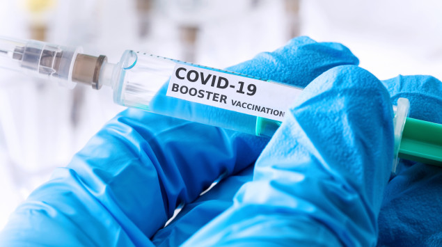 Jemand hält eine Booster-Impfung (Covid-19) in der Hand.