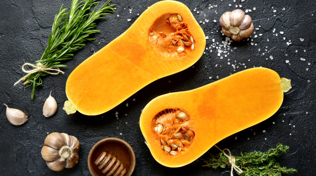 Ein Butternutkürbis liegt aufgeschnitten auf einer Platte