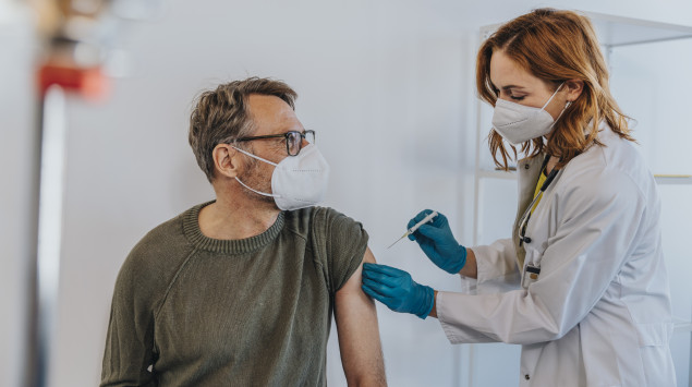 Eine Ärztin impft einen Patienten