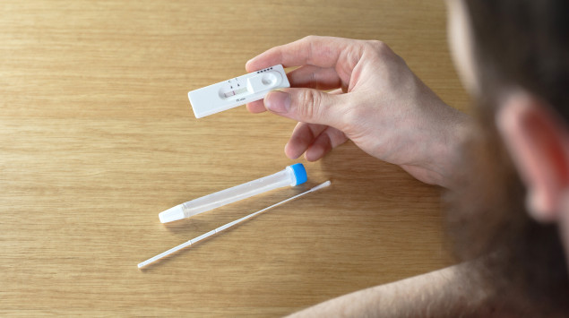 Ein Mann hält einen positiven Corona-Test in der Hand