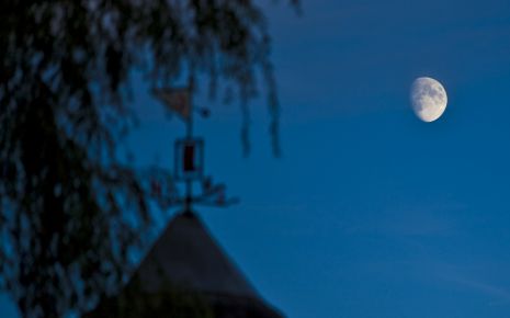 Man sieht den Mond über einem Dach.
