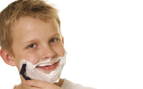 Ein Junge rasiert sich mit einem Nassrasierer.