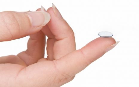 Eine Frau hält eine harte (bzw. formstabile) Kontaktlinse auf dem Zeigefinger.
