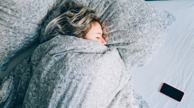 Frau liegt mit Smartphone im Bett