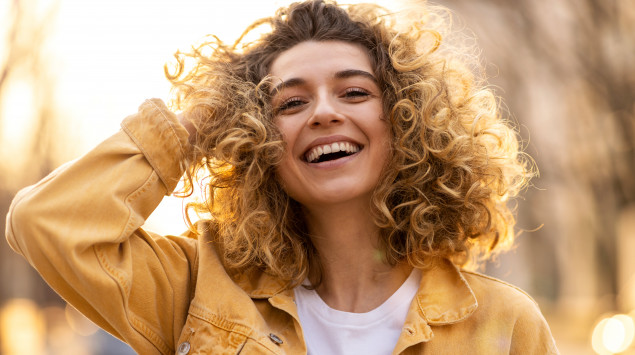 Eine Frau lacht und greift sich in die Haare