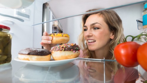 Eine Frau holt sich Donuts aus dem Kühlschrank.