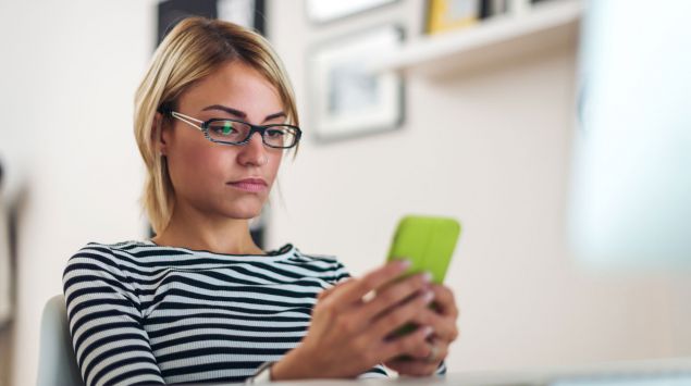 Eine Frau tippt auf ihrem Handy.