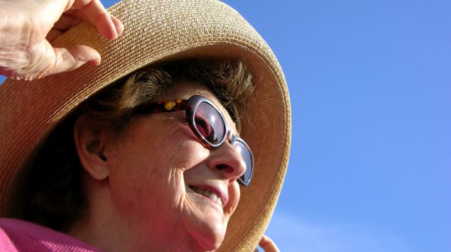 Eine Frau trägt Hut und Sonnebrille.