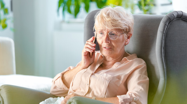 Eine Frau telefoniert und sitzt dabei in einem Sessel.