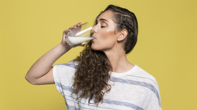 Eine Frau trinkt aus einem Glas Milch.