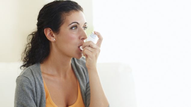 Das Bild zeigt eine junge Frau, die ein Asthmaspray benutzt.