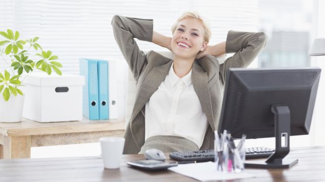 Eine junge Frau sitzt entspannt und lächelnd in ihrem Büro.