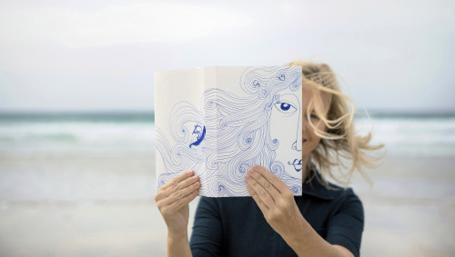 Eine Frau hält eine Zeichnung von ihrem Gesicht vor sich