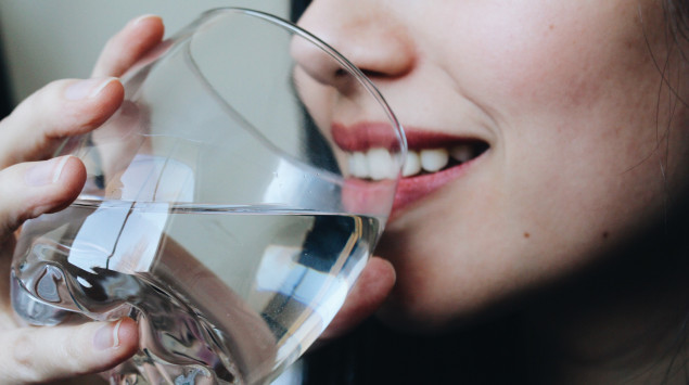 Eine Frau trinkt ein Glas wasser.