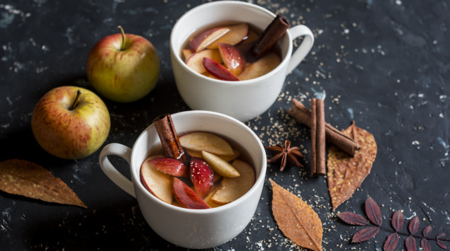 Zwei Tassen mit Glühwein, Äpfeln und Zimt.