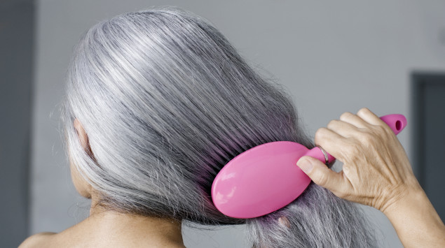 eine Frau kämmt ihre grauen Haare