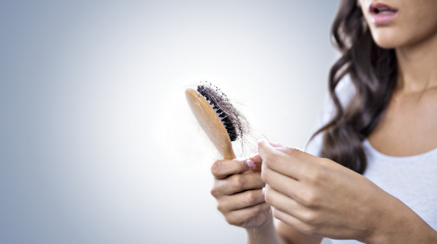Eine Frau hält eine bürste mit vielen Haaren in der Hand