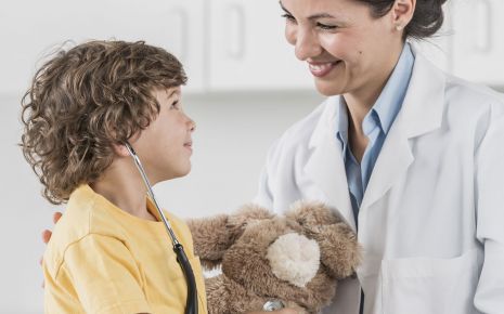 Das Bild zeigt ein Kind beim Arzt mit einem Teddy in der Hand.