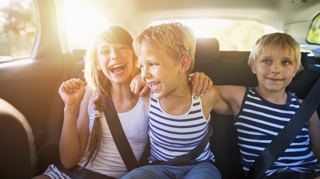 Drei Kinder sitzen angeschnallt im Auto