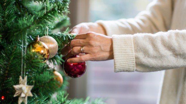 Eine Frau schmückt einen künstlichen Weihnachtsbaum.