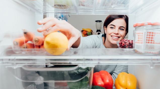 Frau greift in den Kühlschrank
