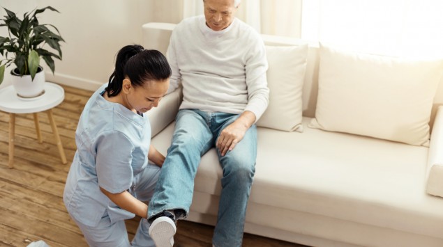 Eine Physiotherapeutin behandelt einen älteren Mann.
