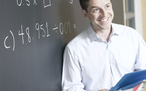 Das Bild zeigt einen Lehrer vor einer Tafel.