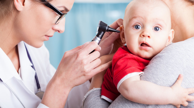 Eine Ärztin schaut einem Baby ins Ohr