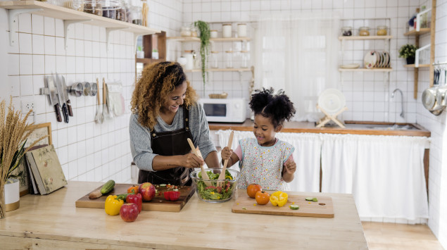 Eine Mutter kocht mit ihrer Tochter gesundes Essen.
