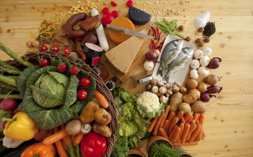 Diabetes Tipps für die Ernährung: Auf einem Tisch liegt eine große Auswahl unterschiedlicher unzubereiteter Lebensmittel.