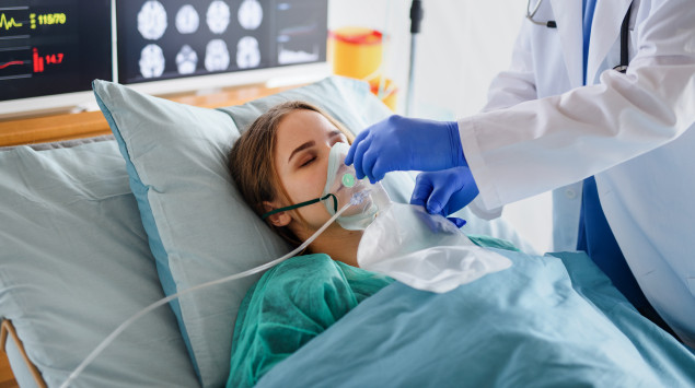 Eine Jugendliche liegt im krankenhausbett, ein Arzt setzt ihr eine Sauerstoffmaske auf
