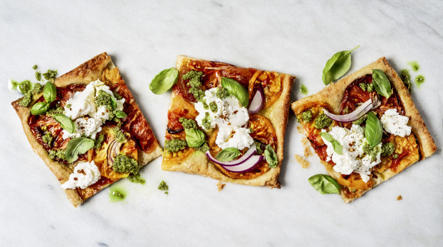 Man sieht mehrere Stücke Pizza mit Gemüse belegt, auf einem weißen Untergrund.