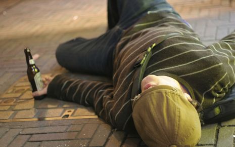Das Bild zeigt einen besoffenen Jugendlichen, der auf der Straße liegt.