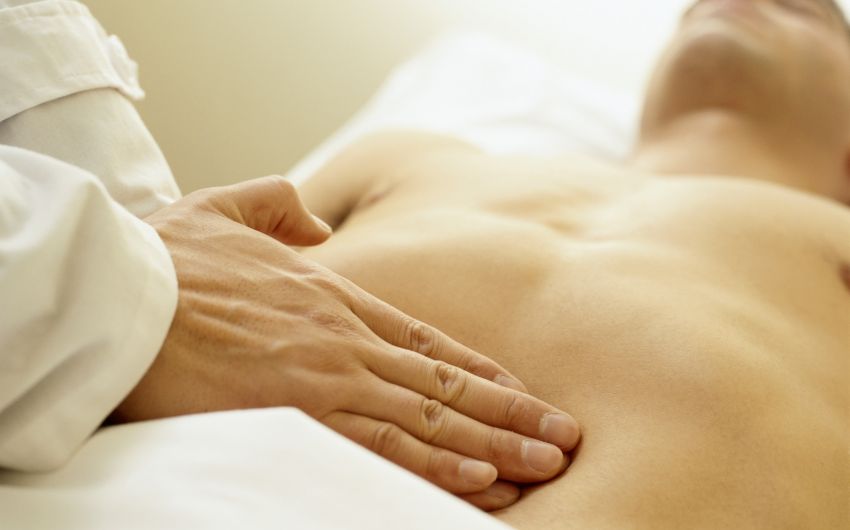 Zwei Hände betasten einen Bauch.