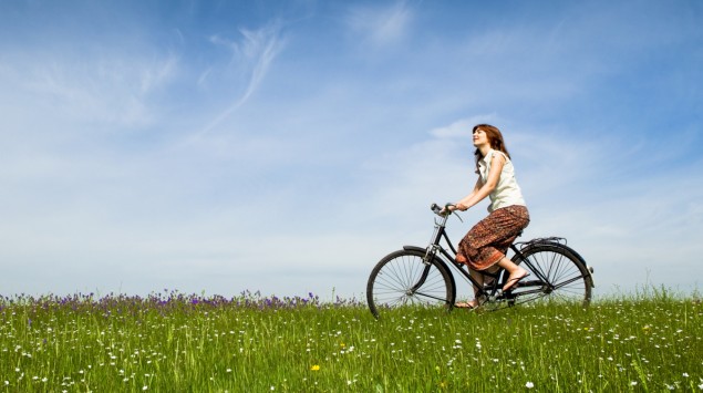 Das Bild zeigt eine Frau, die mit einem Rad über eine Wiese fährt.