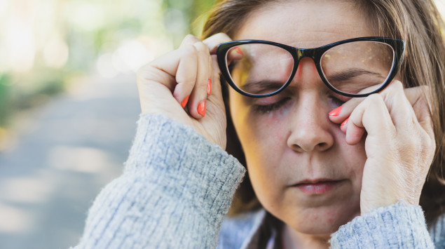 Frühjahrsmüdigkeit: Eine Frau hebt ihre Brille an und reibt sich die Augen.
