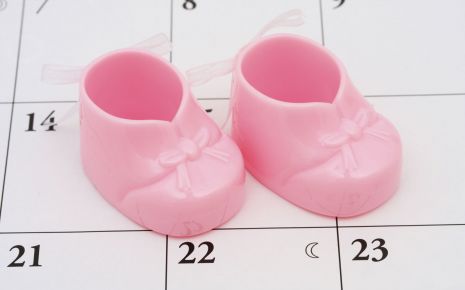 Ein Kalender, darauf ein Paar rosa Babyschuhe.