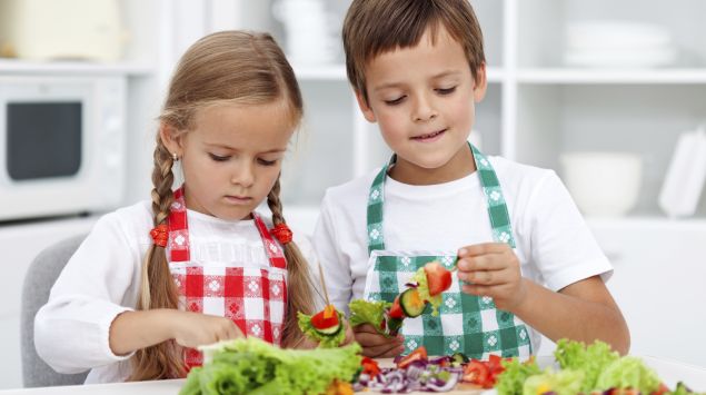 Das Bild zeigt Kinder die Gemüsespieße zubereiten.